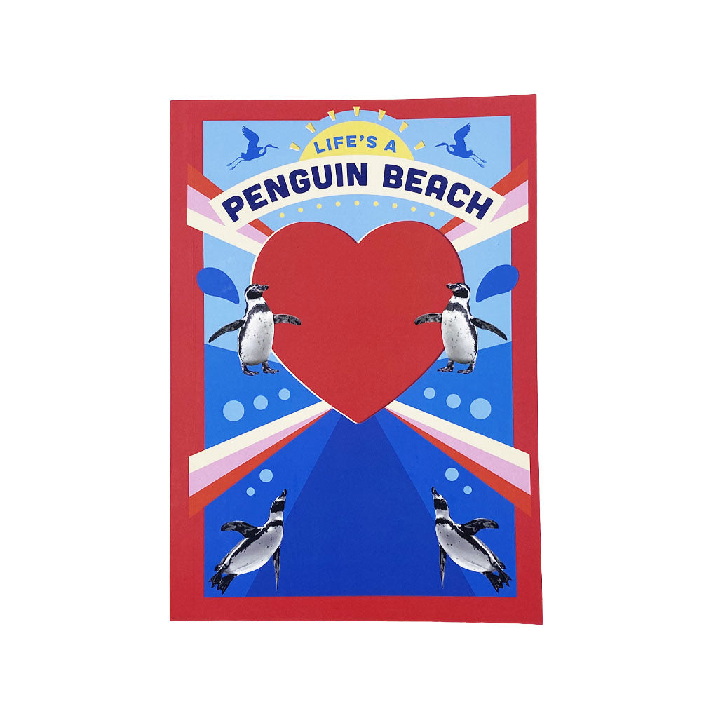 A notebook featuring a red border, a large red heart in the center, penguin illustrations around it, and the text 'LIFE'S A PENGUIN BEACH' on a blue background.