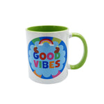 A white ceramic mug with a bright green handle and interior, featuring a colorful 'GOOD VIBES' graphic on the front with a rainbow and blue cloud design.