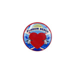A round button badge featuring a red heart, two penguins, and the text 'LIFE'S A PENGUIN BEACH' on a blue and white background.