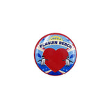 A round button badge featuring a red heart, two penguins, and the text 'LIFE'S A PENGUIN BEACH' on a blue and white background.